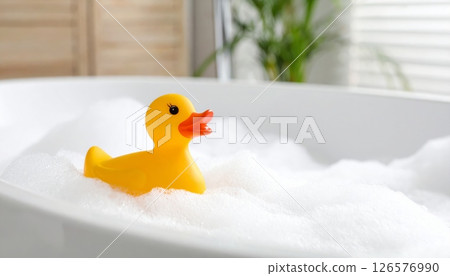 A fun yellow plastic rubber duck toy floats in the baby's bathwater A fun yellow plastic rubber duck toy floats in the baby's bathwater 126576990