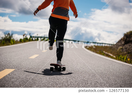 Skateboarder skateboarding on the mountain road 126577130