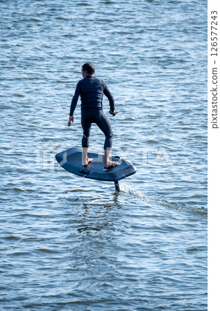 Surfer rides electric hydrofoil board above choppy water Surfer rides electric hydrofoil board above choppy water 126577243