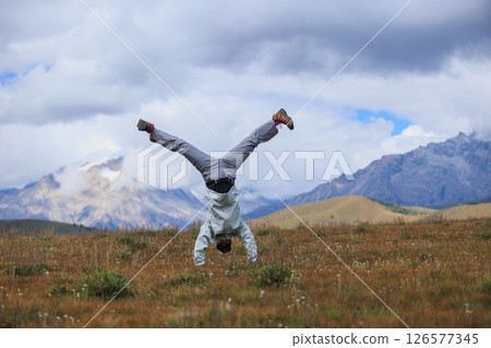 Woman hiker doing a handstand on high altitude mountain meadow 126577345