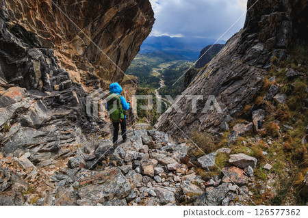 Woman backpacker climbing up on steep cliff edge at high altitude mountains top Woman backpacker climbing up on steep cliff edge at high altitude mountains top 126577362