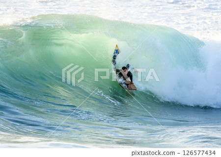Bodyboarder surfing ocean wave 126577434