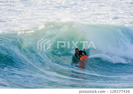 Bodyboarder surfing ocean wave 126577436