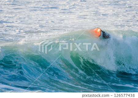 Bodyboarder surfing ocean wave 126577438