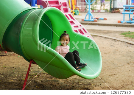 happy toddler baby girl sliding and playing at playground 126577580