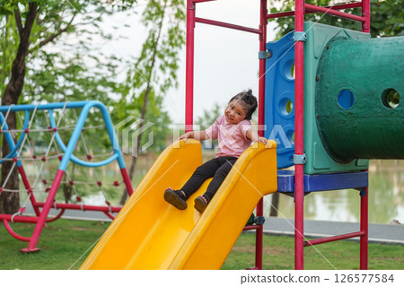 happy toddler baby girl sliding and playing at playground 126577584