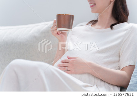 Pregnant woman drinking from a mug 126577631