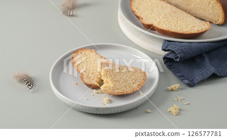 Slices of traditional Portuguese Easter folar on white plates with delicate feathers 126577781