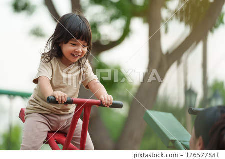 toddler girl and mother playing seesaw in playground 126577881