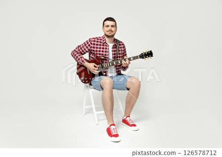 Attractive young guy playing the guitar on a white background 126578712