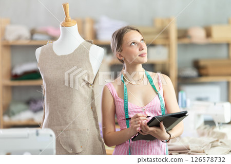 Woman dressmaker makes pattern using tablet Woman dressmaker makes pattern using tablet 126578732