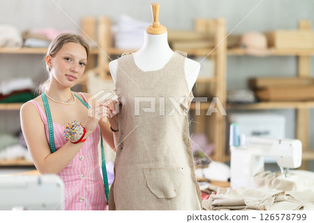 Positive young female dressmaker working with mannequin 126578799