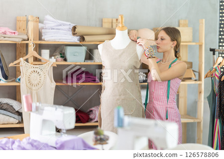 Designer in dress standing near mannequin in workshop 126578806