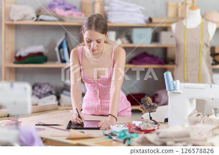 woman stands with a tablet in her hands in a sewing workshop 126578826