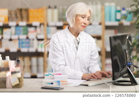 Mature female pharmacist working at computer Mature female pharmacist working at computer 126578860