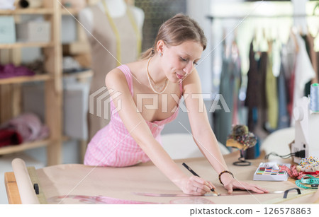 Woman tailor drawing on paper in workshop Woman tailor drawing on paper in workshop 126578863