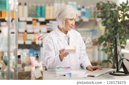 Portrait of mature female pharmacist working in a modern drugstore and offering to buy pills 126578878