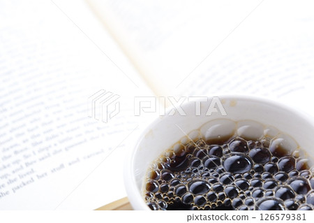 拿著一本打開的書(西洋書)和一個裝有咖啡的咖啡杯,一邊喝咖啡一邊享受閱讀的形象。 拿著一本打開的書(西洋書)和一個裝有咖啡的咖啡杯,一邊喝咖啡一邊享受閱讀的形象。 126579381