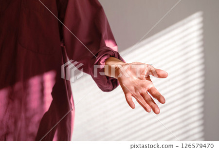 Person Reaching Out Hand in Dappled Shadow of Window Blind on Wall. Offer Help or Assistance. Trust Concept. Person Reaching Out Hand in Dappled Shadow of Window Blind on Wall. Offer Help or Assistance. Trust Concept. 126579470