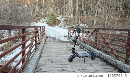 Electric Scooter on Bridge in Winter Landscape, Outdoor Adventure and Eco-Friendly Transportation 126579843