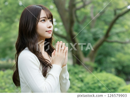 A woman praying with her hands together A woman praying with her hands together 126579903