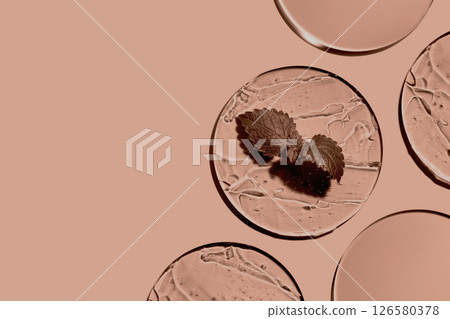 Sample of gels cosmetic product and leaf in petri dish in mocha mousse color 126580378