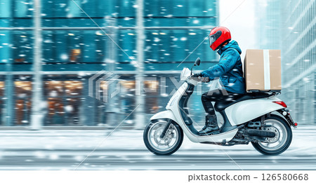 Male delivery rider on scooter in snowy urban setting with red helmet 126580668
