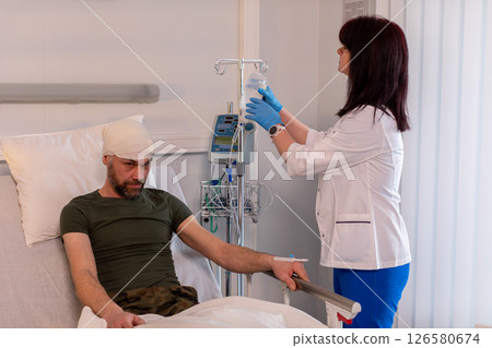 A patient is in a hospital, and a nurse is caring for them, ensuring their comfort 126580674