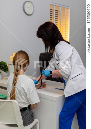 A female healthcare professional is measuring a patients blood pressure in a clinic setting A female healthcare professional is measuring a patients blood pressure in a clinic setting 126580690