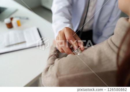 Physical Examination and Patient Interaction. A doctor uses a stethoscope during a medical checkup, ensuring attentive care. 126580862