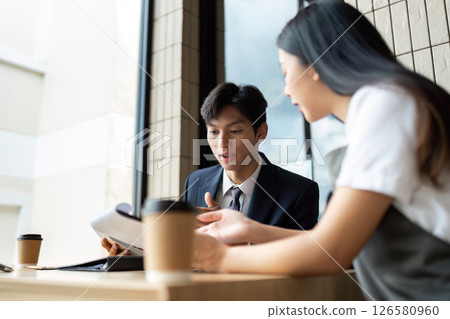 Business Collaboration. Colleagues discussing project plans over coffee in a modern cafe. Business Collaboration. Colleagues discussing project plans over coffee in a modern cafe. 126580960