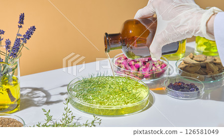 Scientist stirring green herbal infusion during natural cosmetic formulation using essential oils and dried flowers. Oil of tea tree is many use 126581049
