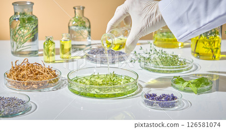 Pouring green herbal liquid into clear glass dishes for testing and examination in a controlled lab environment. Pharmaceutical research warning with herbal green pharmaceuticals 126581074
