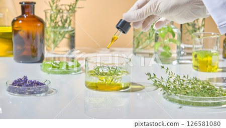 Hand of a lab technician gently mixing essential oils and herbal solutions with natural ingredients like lavender and leaves. Front view Hand of a lab technician gently mixing essential oils and herbal solutions with natural ingredients like lavender and leaves. Front view 126581080