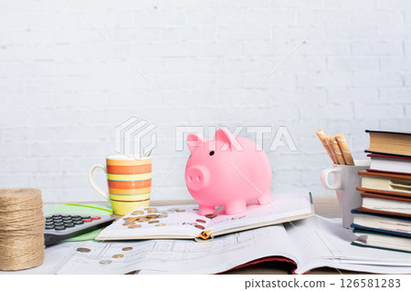 Effective Financial Planning with a Pink Piggy Bank and Essential Workspace Tools 126581283