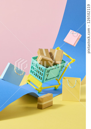 A mint green mini shopping cart with colorful boxes and shopping bags decorated on a colorful paper background. Vertical photo frame for social media, convenient shopping theme 126582119