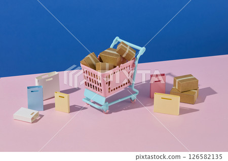 Two pink shopping carts filled with parcels and surrounded by boxes and bags on a light pink-blue paper background, evoking a feeling of shopping spree. Shopping theme with creative handmade props Two pink shopping carts filled with parcels and surrounded by boxes and bags on a light pink-blue paper background, evoking a feeling of shopping spree. Shopping theme with creative handmade props 126582135