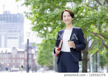 Business: A woman walking through an office district with a coffee cup 126582379