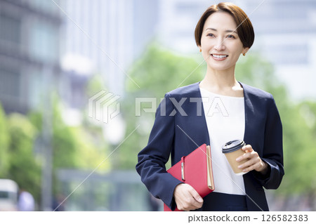 商業：一位女士手捧咖啡杯穿過辦公區 126582383