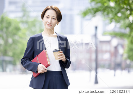 商業：一位女士手捧咖啡杯穿過辦公區 126582384