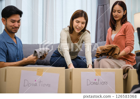 group of friend sorting and packing clothes into a donation box.community support, and charitable giving group of friend sorting and packing clothes into a donation box.community support, and charitable giving 126583368