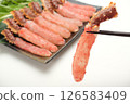 A red king crab is being held up with chopsticks. The background is white. 126583409