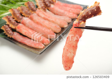 他正用筷子夾起一份生的帝王蟹涮鍋。背景是白色的 他正用筷子夾起一份生的帝王蟹涮鍋。背景是白色的 126583409
