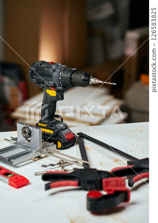 Electric cordless drill with bits and hand tools on workbench in workshop. Home renovation, construction and repair concept 126583825