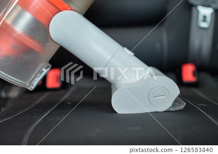 Handheld cordless vacuum cleaner vacuuming car seat upholstery. Modern car interior cleaning and maintenance 126583840