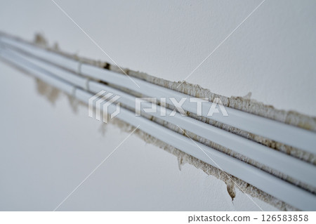 Close-up of white electrical cables embedded in wall groove during wiring installation. Concept of electrical work, construction or renovations 126583858