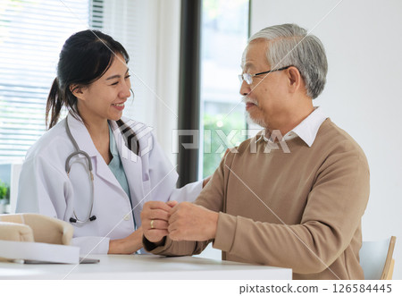 Doctor happily informs senior patient about full recovery during follow-up checkup in hospital setting Doctor happily informs senior patient about full recovery during follow-up checkup in hospital setting 126584445