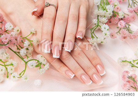 Woman showing french manicure on pink background with flowers 126584903
