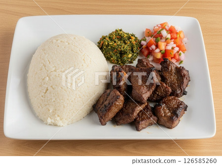 Tanzania Ugali Nyama Choma with greens and tomato relish 126585260