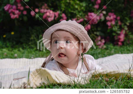 Child Lying on Blanket Surrounded by Pink Flowers 126585782